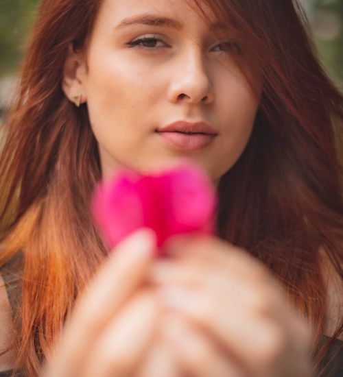 A serene person gently closing their eyes with a soft pink light halo effect.